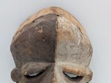 an old wooden mask on a white surface with a gray background