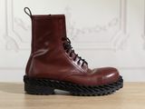 des bottes en cuir rouge à semelles noires posées sur une table en bois