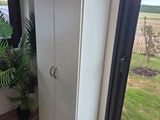 une armoire blanche dans un coin d'une pièce dotée d'une grande fenêtre