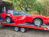 une voiture rouge à l'arrière d'une remorque à plateau