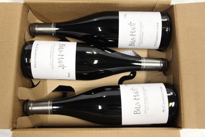 three bottles of wine are in a cardboard box on a table