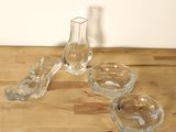 trois bols en verre et un vase en verre posés sur une table en bois