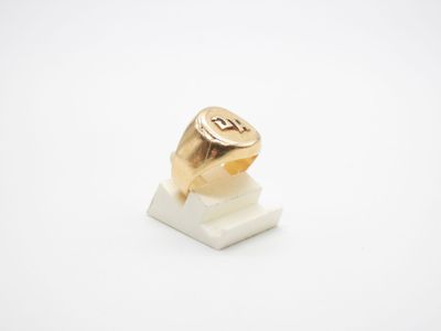 un gros plan d'une bague en or posée sur un bloc de marbre