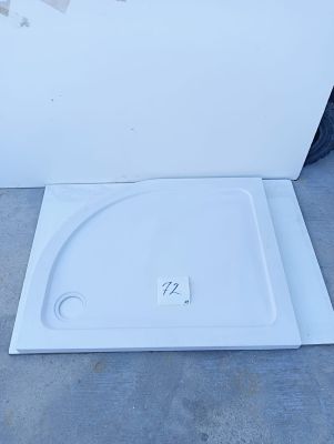 a close up of a white shower tray sitting on the ground