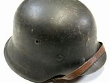 an old black helmet with a leather band on a white surface