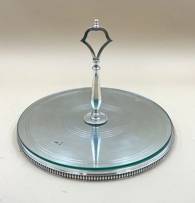 un plat à gâteau en argent surmonté d'un plateau en verre
