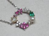 un collier composé de perles blanches, roses et vertes posé sur une table