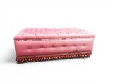 a pink ottoman that is sitting on a white surface