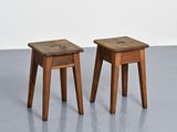 two small wooden stools sitting on top of a cement floor
