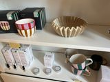 a shelf that has a bowl, cups, and other items on it