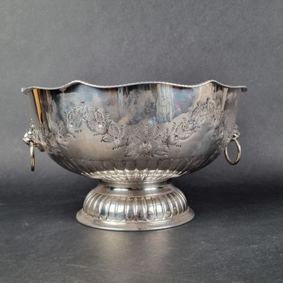 un bol ancien plaqué argent posé sur un socle, sur fond gris