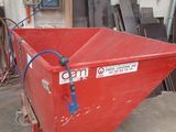 a red dumpster sitting in a garage next to a pile of wood