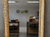 un miroir ancien dans un cadre doré posé sur un parquet, dans une pièce