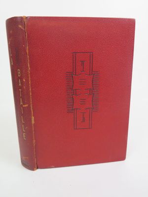un vieux livre rouge posé sur une table blanche
