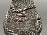 a silver vase with a dragon on it on a table
