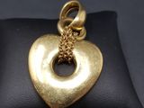 a close up of a gold heart pendant on a black pillow
