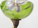 a green vase with flowers painted on it on a stand