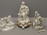 trois statues blanches représentant des personnages et des animaux, posées sur une table