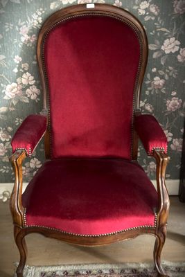 a red chair sitting in a room with a floral wallpaper