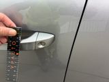 a person holding a ruler that is on the door of a car