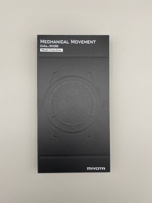 une boîte contenant une calculatrice à mécanisme mécanique posée sur une table