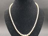 un collier de perles blanches sur un mannequin avec un fermoir en or