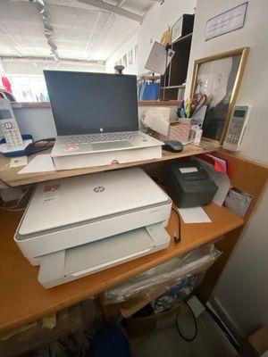 a laptop computer sitting on top of a printer on a desk