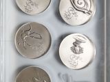 three silver coins in a clear display case with writing on them