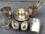 a silver plate with a spoon, cup, and other silverware on a table