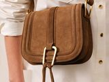une femme portant une chemise blanche et un sac à main marron