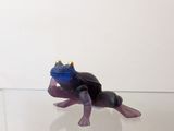 une figurine représentant une grenouille assise sur une étagère en verre