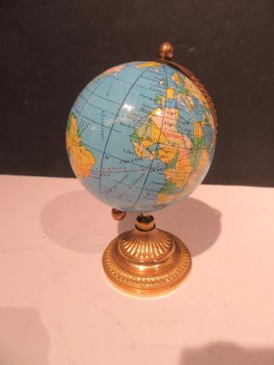 un petit globe bleu et doré posé sur une table blanche