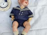 a doll that is laying on the ground next to a hat