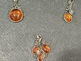 three pieces of silver and amber jewelry sitting on top of a table