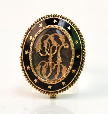 une image représentant une bague dorée et noire ornée d'un monogramme