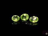 three green gems on a black surface with a black background