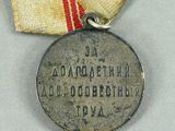 an old medal with a ribbon around it on a white surface