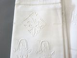 three white napkins with embroidered designs on them sitting on a table
