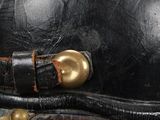 an old black leather hat with a gold buckle on a black background