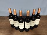 six bottles of wine are lined up on a wooden table