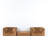 une photo d'un canapé et d'un pouf en cuir marron dans une pièce blanche