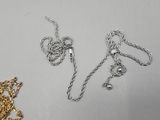 two pieces of silver and gold necklaces on a white surface