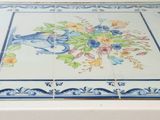 a blue and white tile with a vase of flowers on it