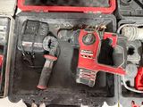 a red and black drill in a case with other tools