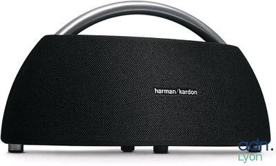 a black speaker sitting on top of a table next to a white wall
