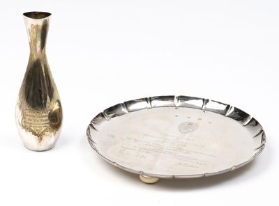 un plateau en argent et un vase en argent posés sur une table blanche
