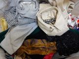 a pile of clothes sitting in a suitcase on a bed