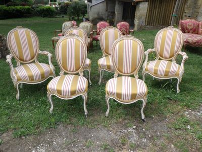 several chairs and a table in a field of grass with a house in the background