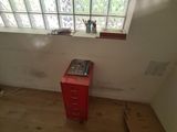a red cabinet in the corner of a room next to a window