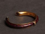a close up of a gold and red bracelet on a black surface